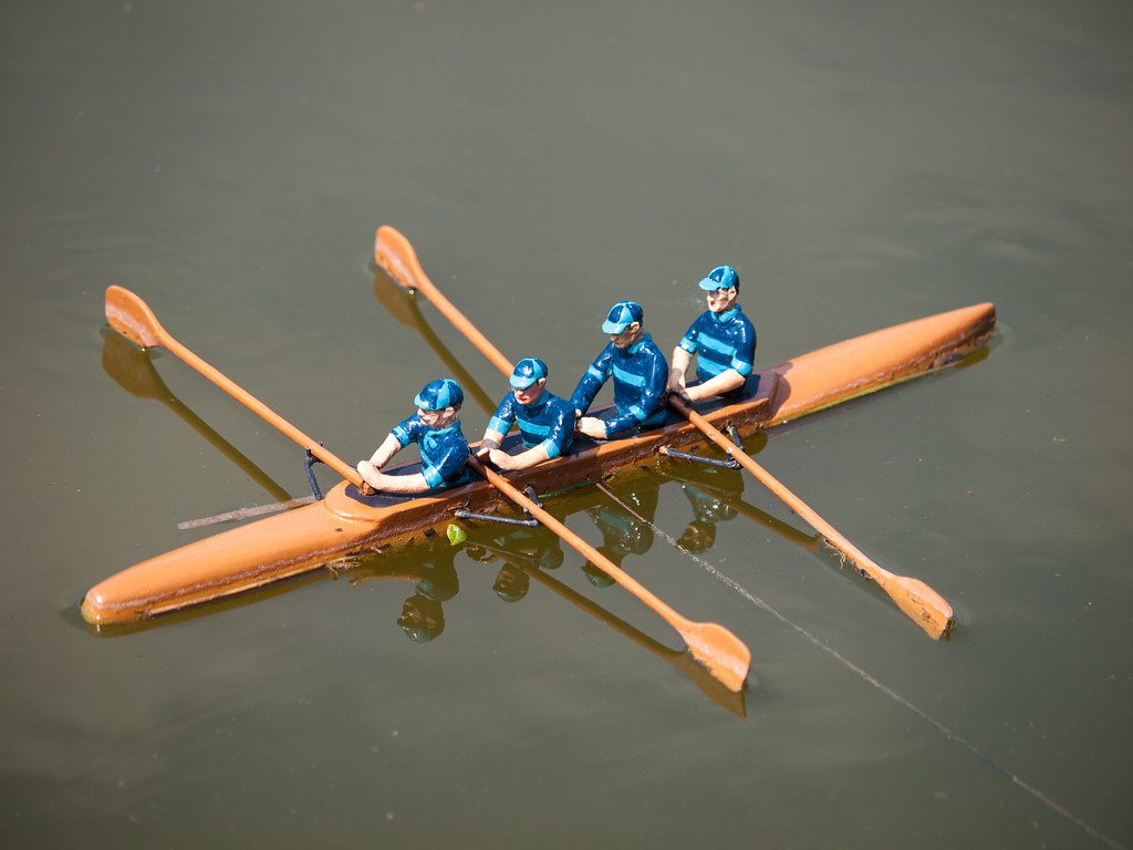 Four rowers in orange boat on water