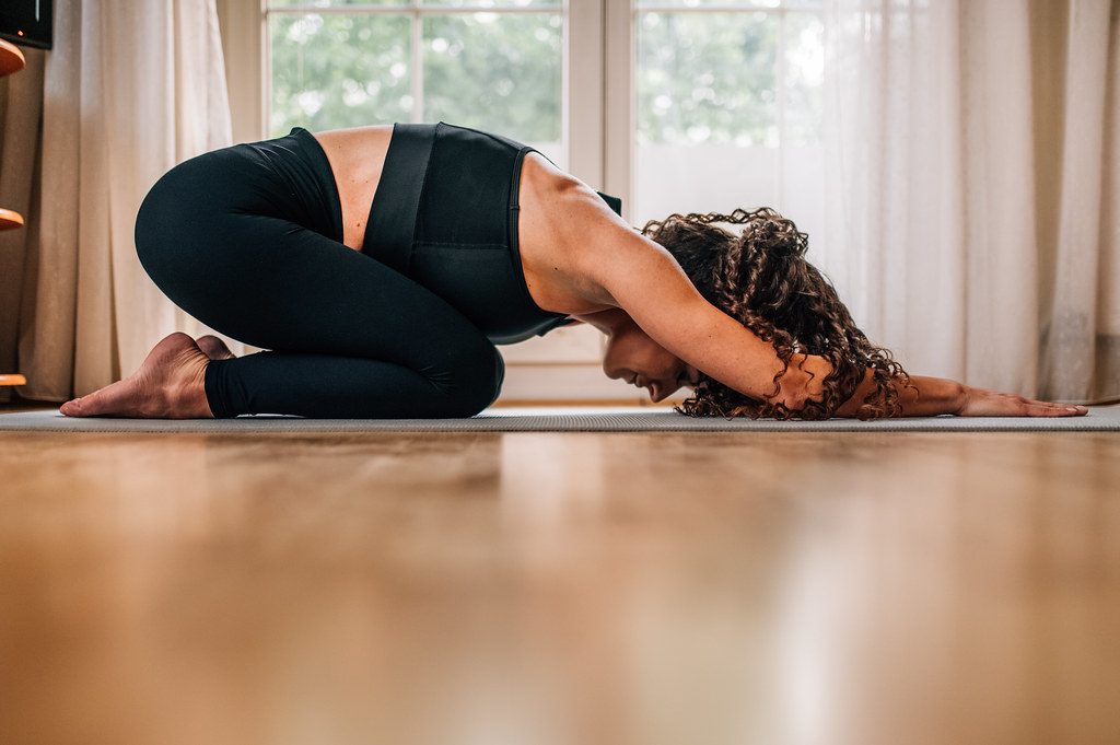Woman in child's pose on wooden floor