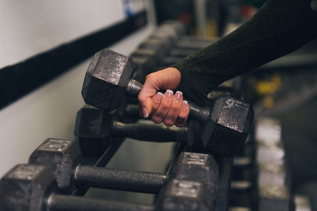 Hand lifting dumbbell from rack