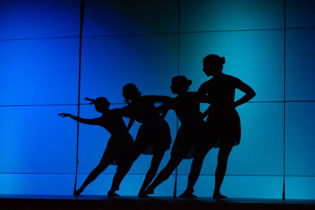 Silhouettes of dancers on blue stage