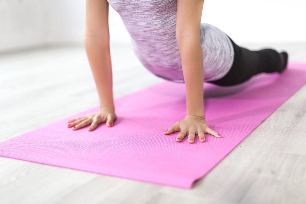 Person on yoga mat doing a pose, cropped