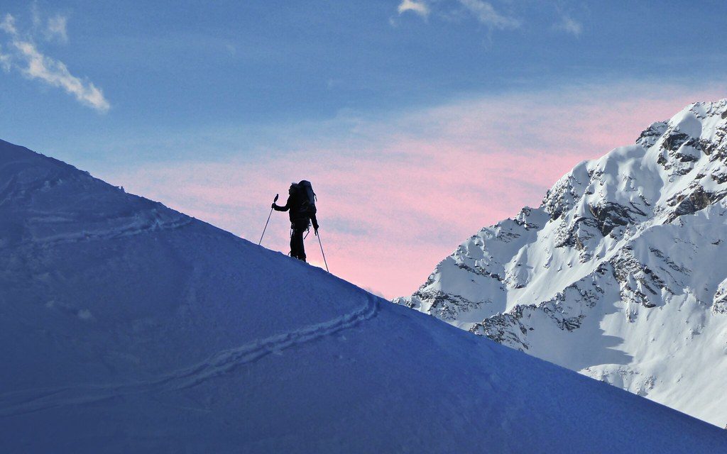 Ski tourer silhouetted on snowy ridge