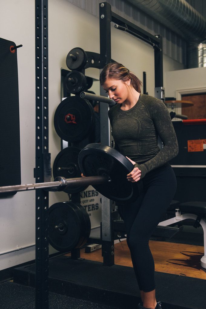 Woman loading plates on barbell rack