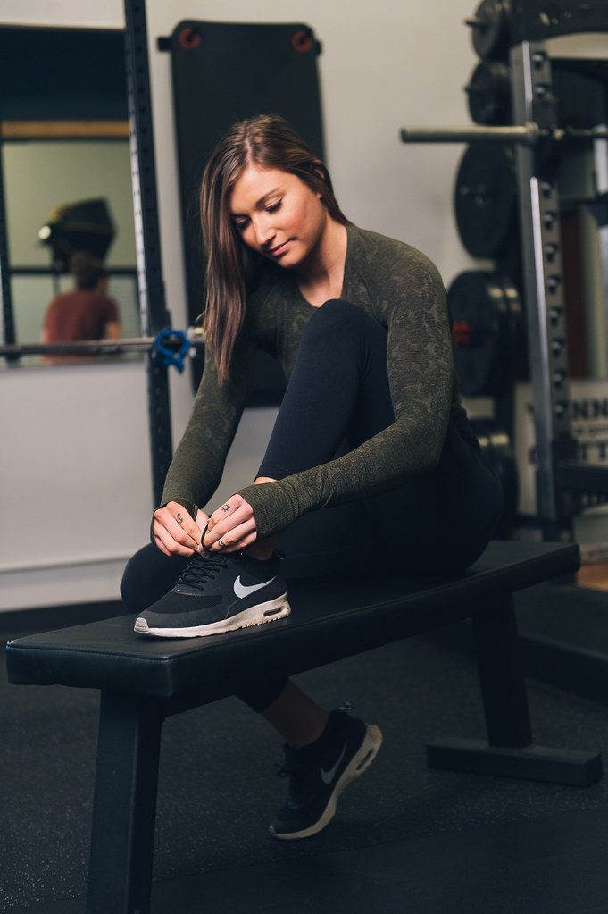 Woman tying shoe on gym bench
