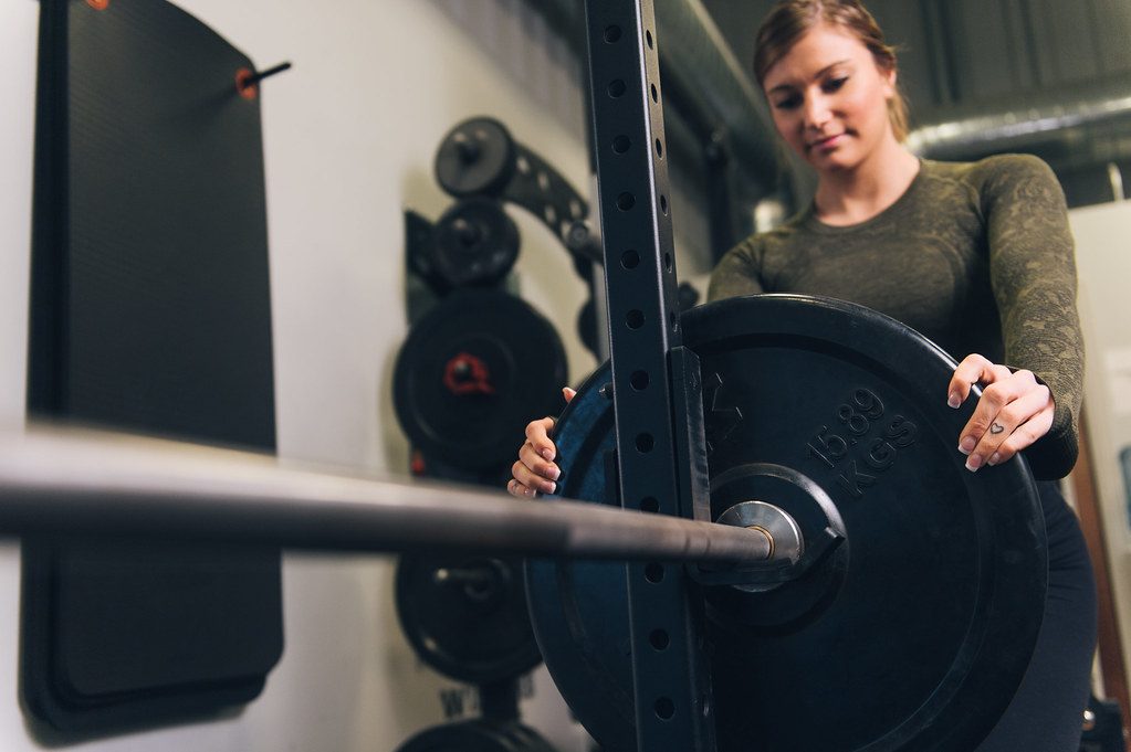 Woman loading plate onto barbell